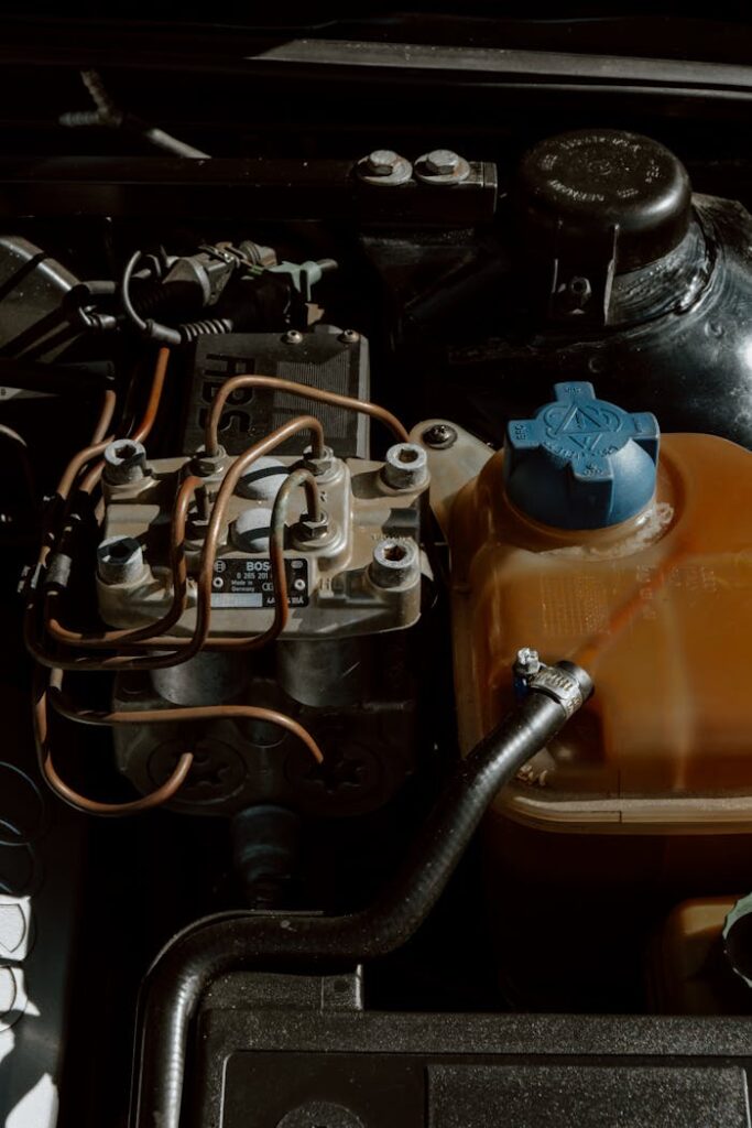 pexels-photo-6110229 Detailed view of automobile engine parts and mechanisms with wiring and fluid container.